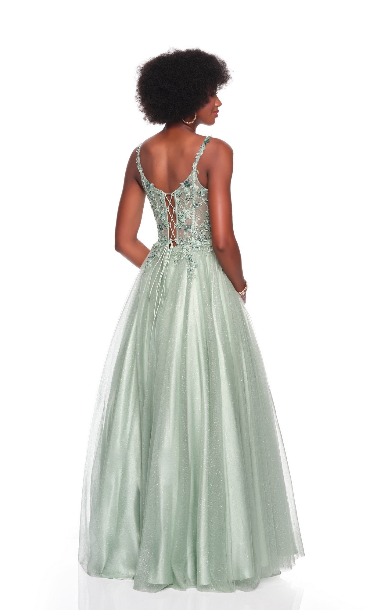 A woman wears the Dave and Johnny 12882 long prom dress, sleeveless and light green with a lace-embroidered corset bodice, floral lace details, lace-up back, and flowing tulle A-line skirt, standing against a white backdrop.